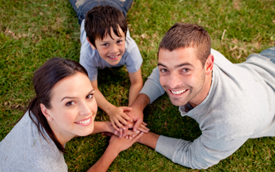 Woman and man with boy, laying on grass holding hands